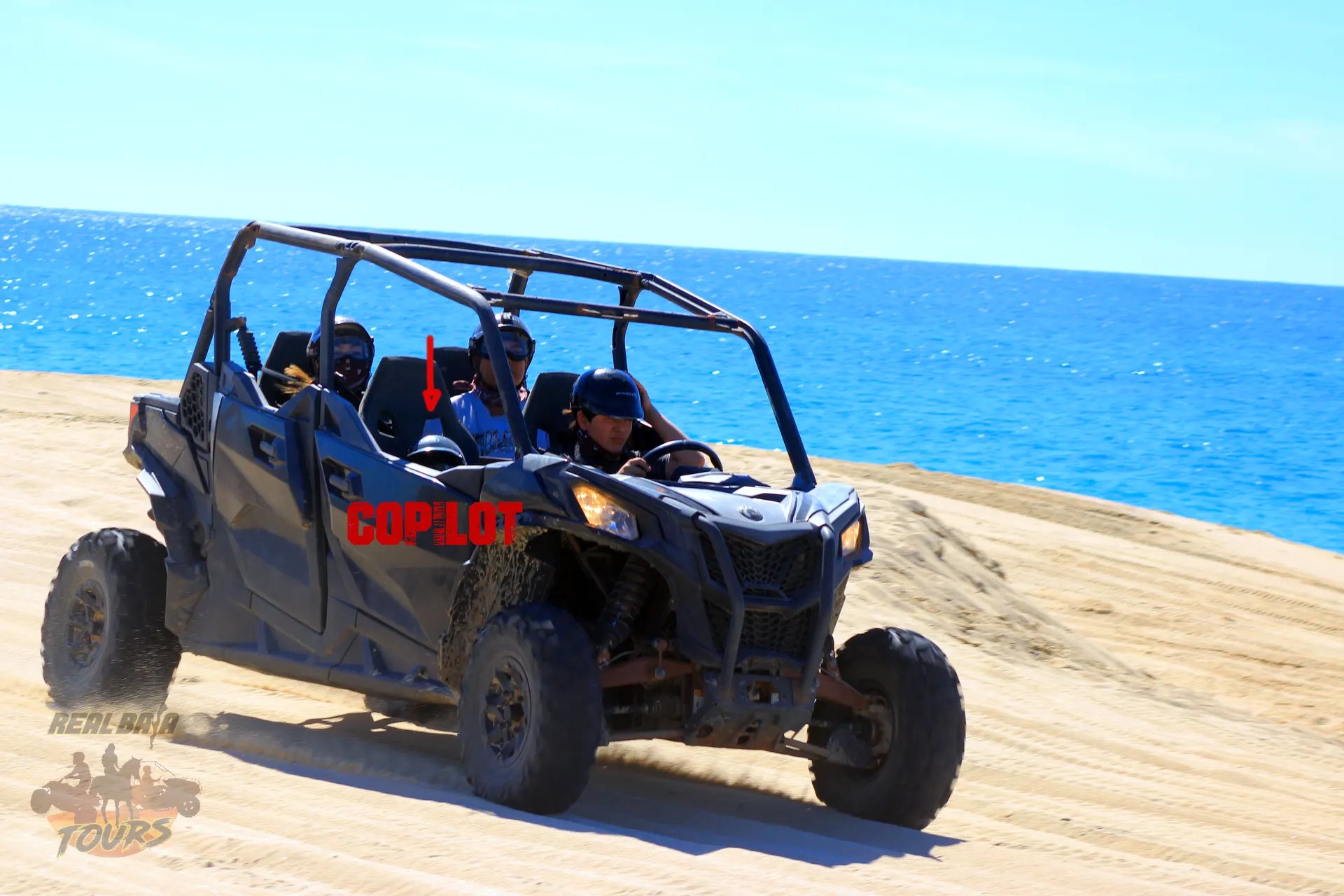 Blue QUAD UTV buggy with tourists riding on sandy beach with turquoise ocean water in Baja California Sur