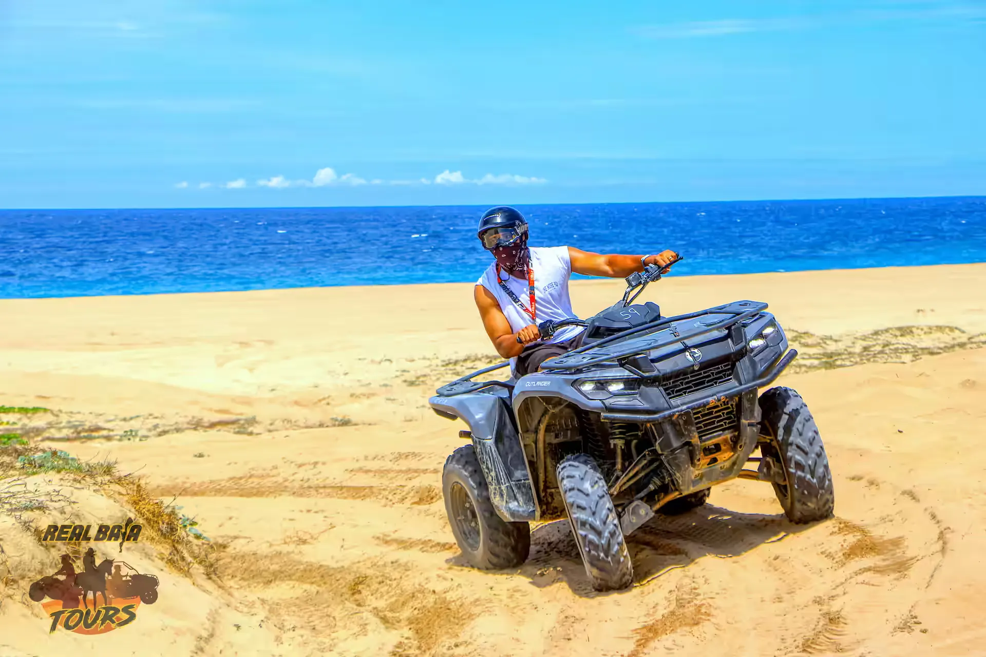 Adventure rider on ATV on sandy beach with turquoise ocean and blue sky in Baja California Sur