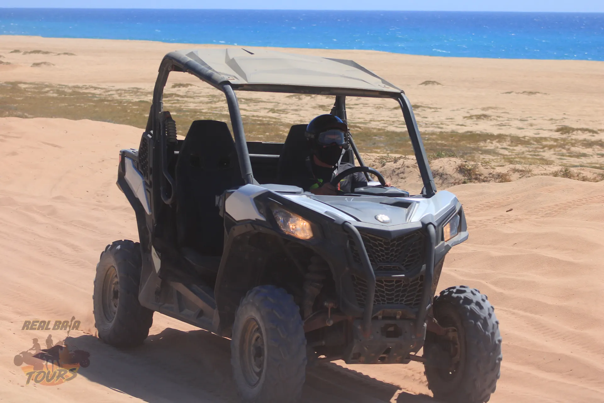 UTV buggy parked on sandy beach with crystal blue ocean and desert landscape in Baja California Sur