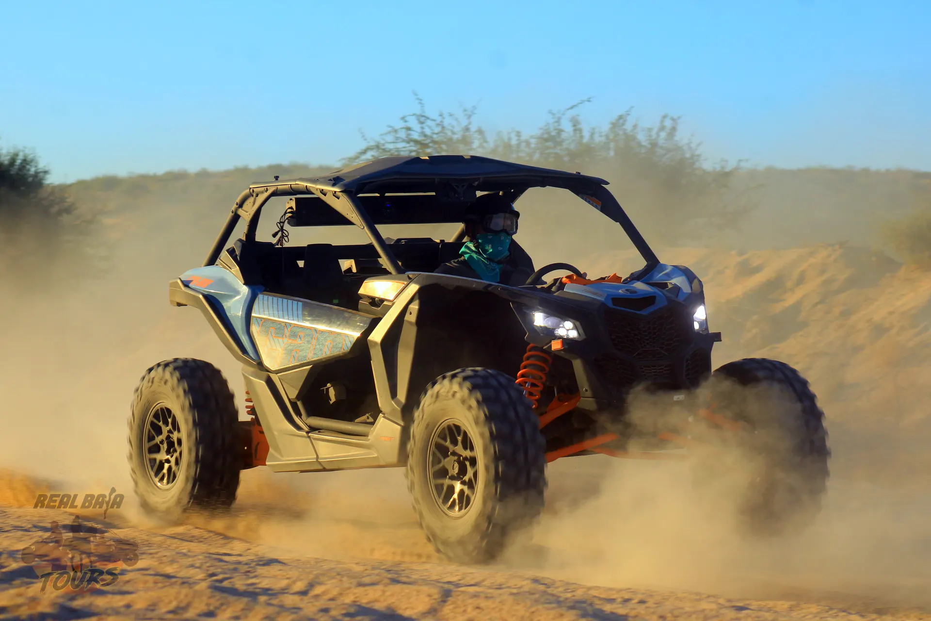 Orange and black UTV kicking up dust while driving through desert terrain road to candelaria  in Cabo San Lucas