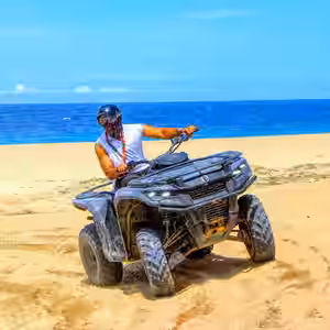 Adventure rider on ATV on sandy beach with turquoise ocean and blue sky in Baja California Sur