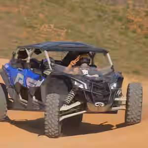 Blue and black UTV buggy driving on sandy desert trail in Baja California Sur with sparse vegetation