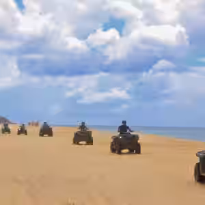 Group of ATV riders on a sandy beach in Baja California Sur with ocean and cloudy sky